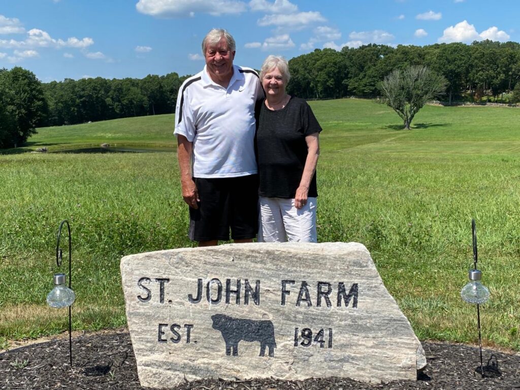 Larry and Laurel St. John in front of stone marker
